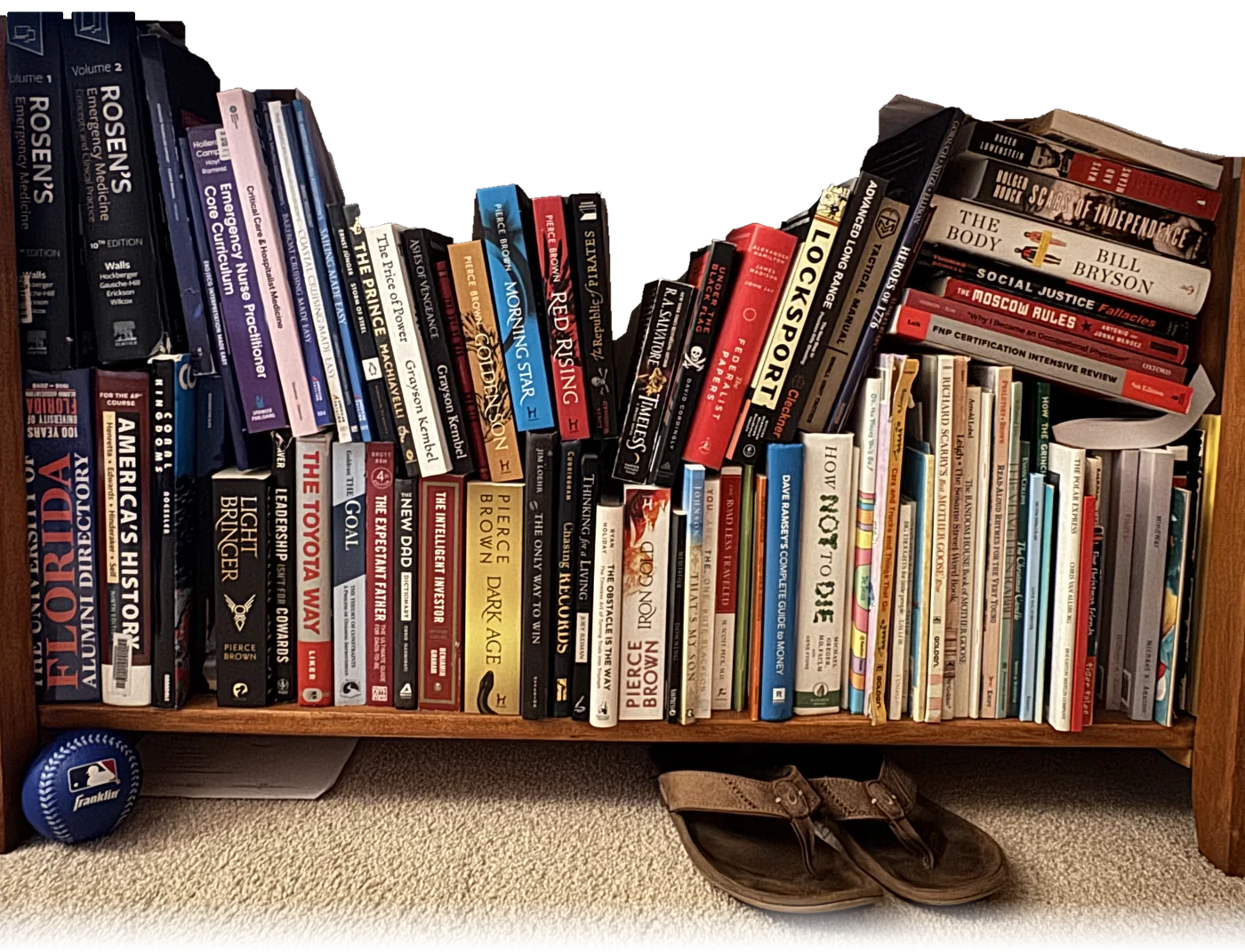 Ian's bookshelf at home: Rosen's Emergency Medicine, the Pierce Brown books, The Republic of Pirates and more, with his baseball and sandals on the floor beneath